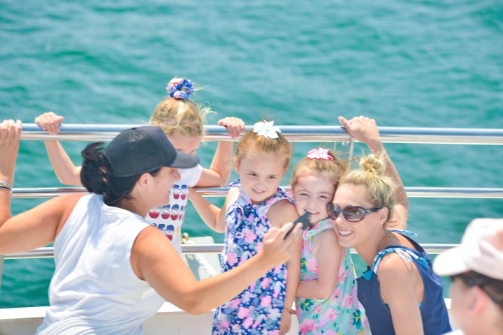 Group of people taking a selfie on a boat with ocean in background.