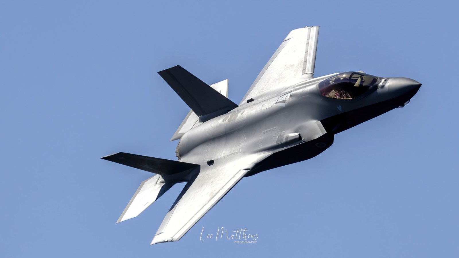 a fighter jet flying through a blue sky