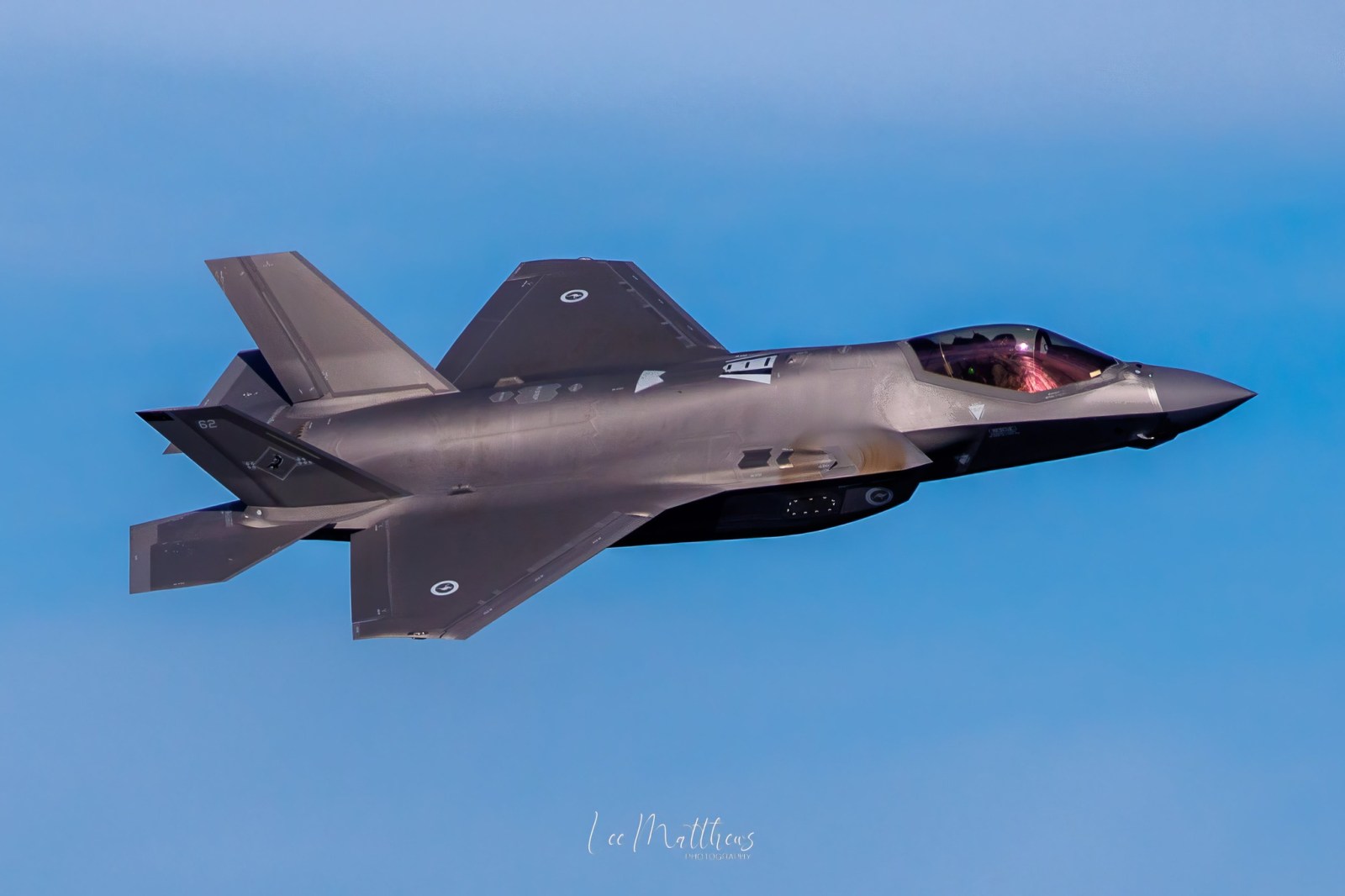 a fighter jet flying through a blue sky