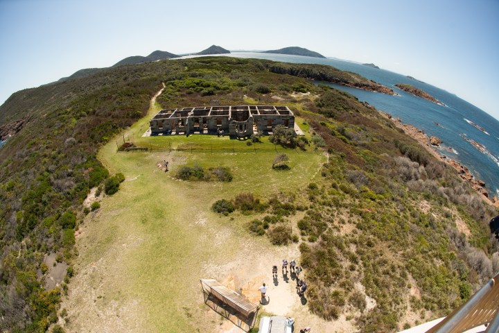 Aerial view of a hilltop building with ocean and mountains in the background.