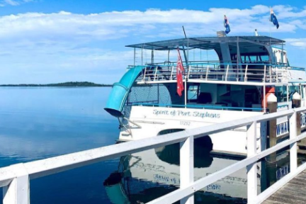 Boat docked at pier on calm blue lake under clear sky.